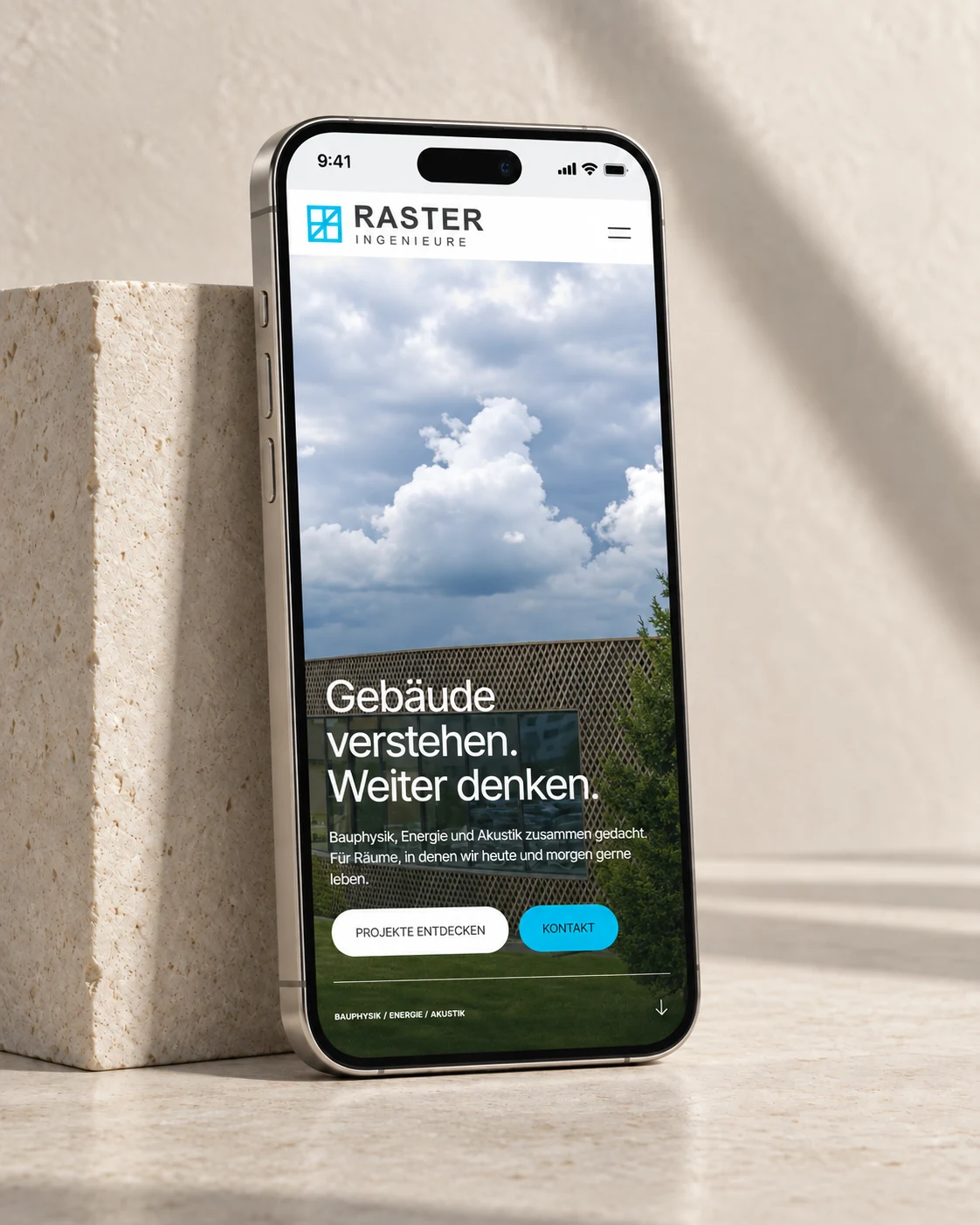 Mobile RASTER-Website auf einem iPhone vor hellem Naturstein